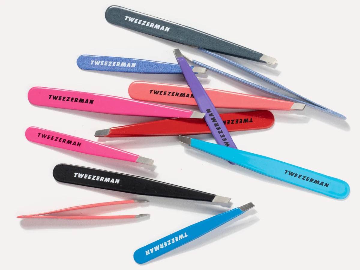 Collection of colorful Tweezerman tweezers in various styles and sizes arranged on a white background