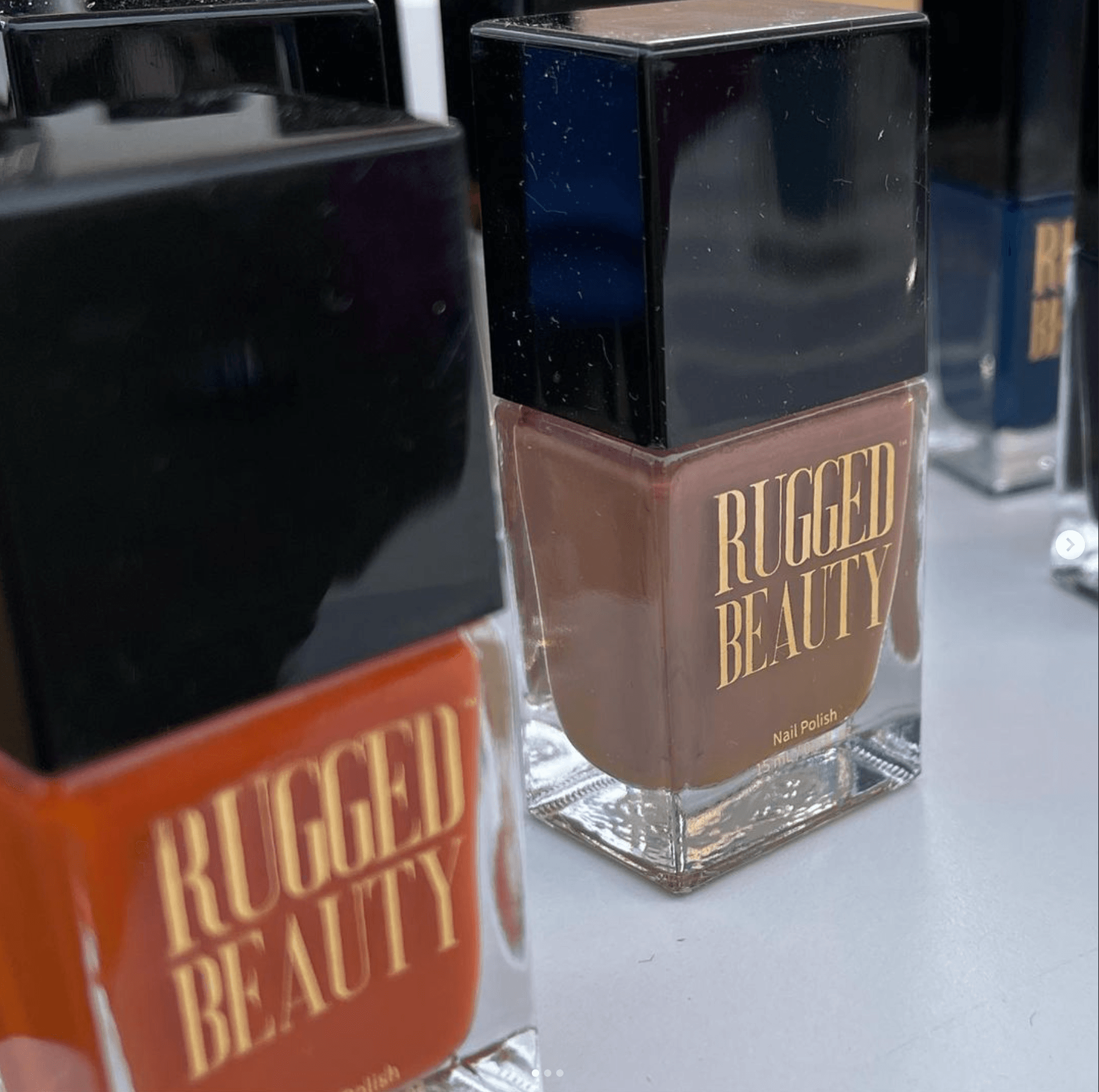 Close-up of Rugged Beauty nail polish bottles in various earthy shades with black caps on display