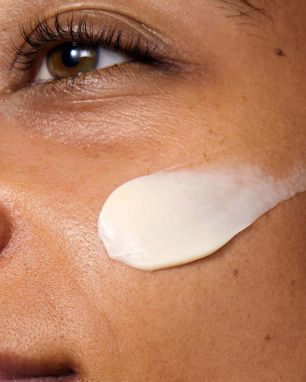 Close-up of a person's face with a smear of cream on their cheek