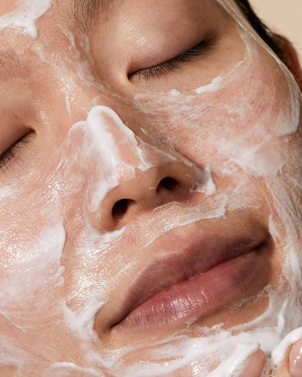 Close-up of a person applying a facial mask with their fingers.