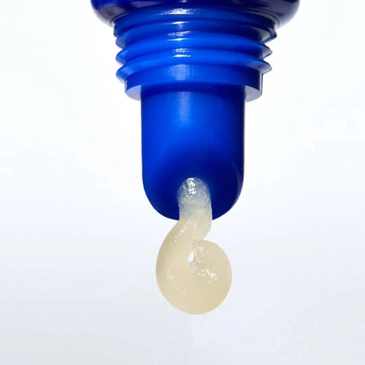 Blue bottle cap with a small amount of beige liquid on a white background