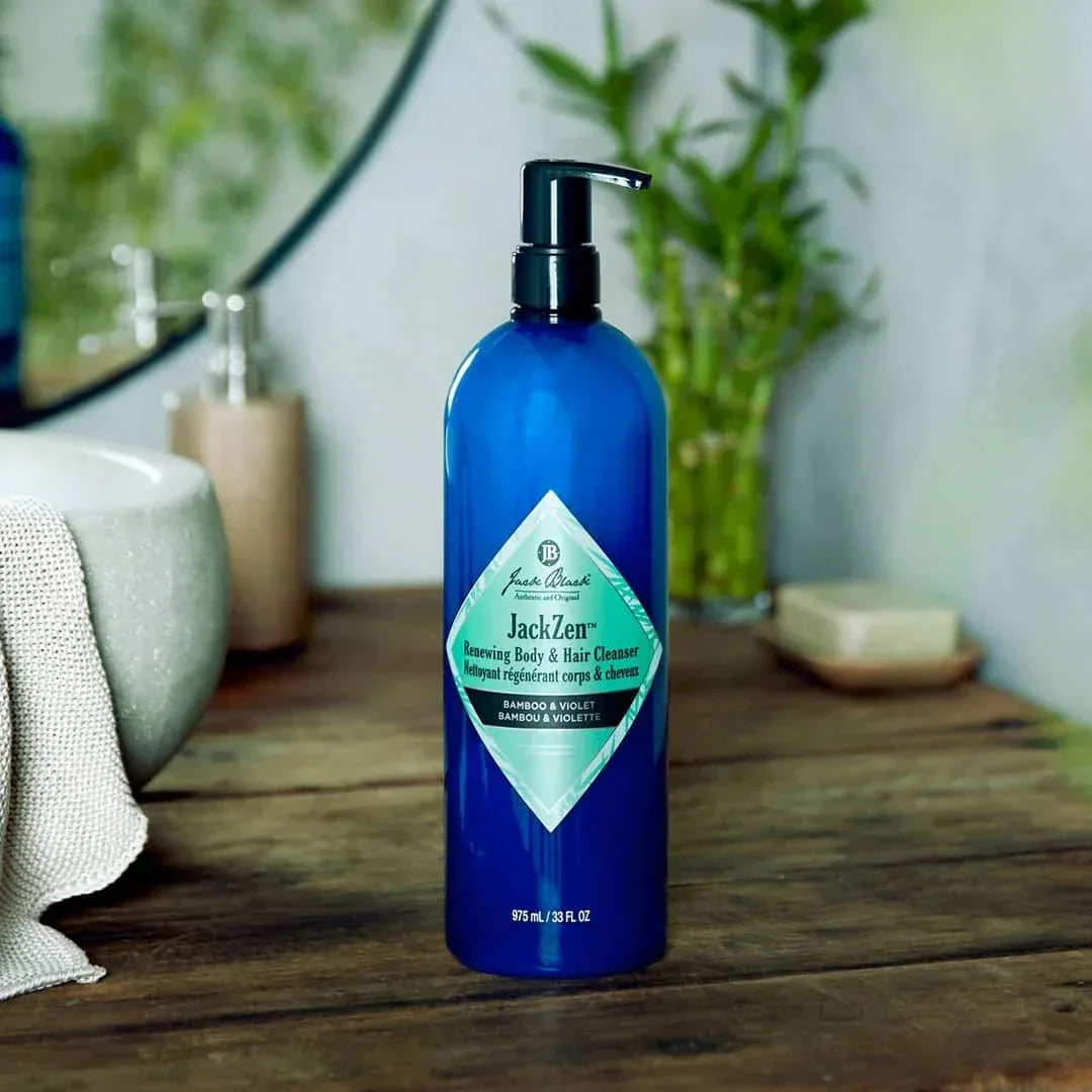 Blue bottle of Jack Black product on a wooden surface with a bathroom setting in the background.