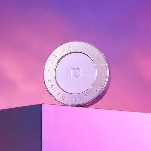 Natura Bisse Age Defying Body Cream in a sleek round container on pink and purple gradient background