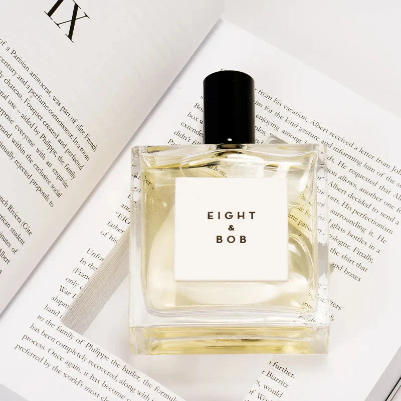 Eight Bob The Original perfume bottle with clear glass and black cap on open book pages