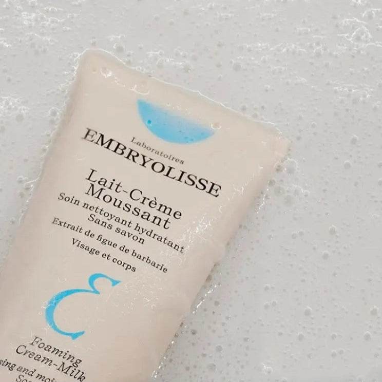 Embryolisse Foaming Cream Cleanser tube on a bubbly foamy surface for face and body cleansing