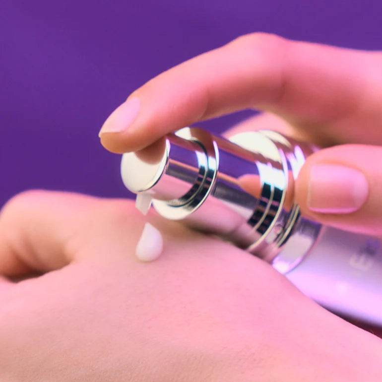 Natura Bisse Energizing Rejuvenating Luxury Serum being dispensed onto hand from silver pump bottle