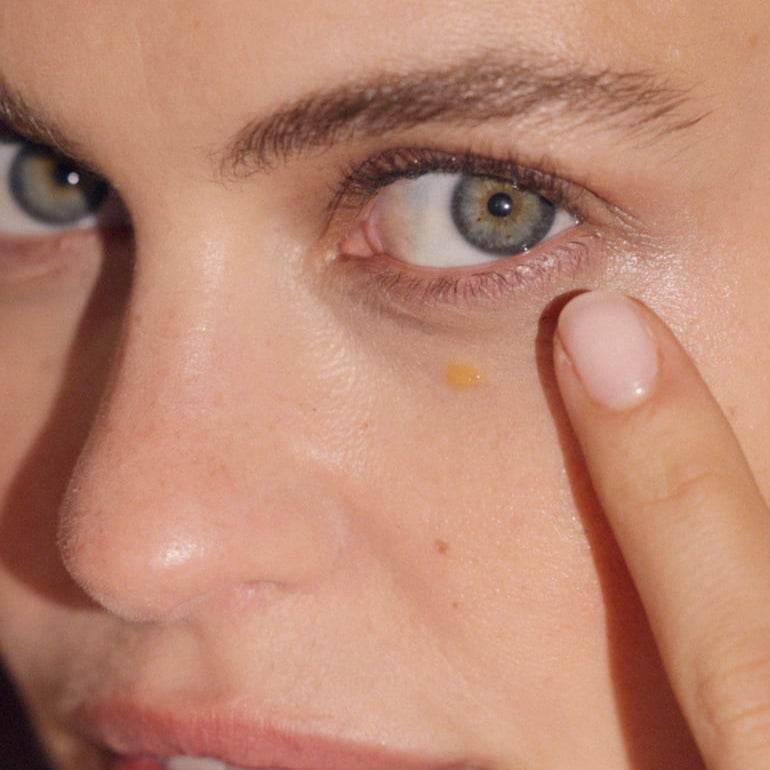 Close-up of woman applying Natura Bisse Gel With Ginseng And Vitamin C under her eye for skincare