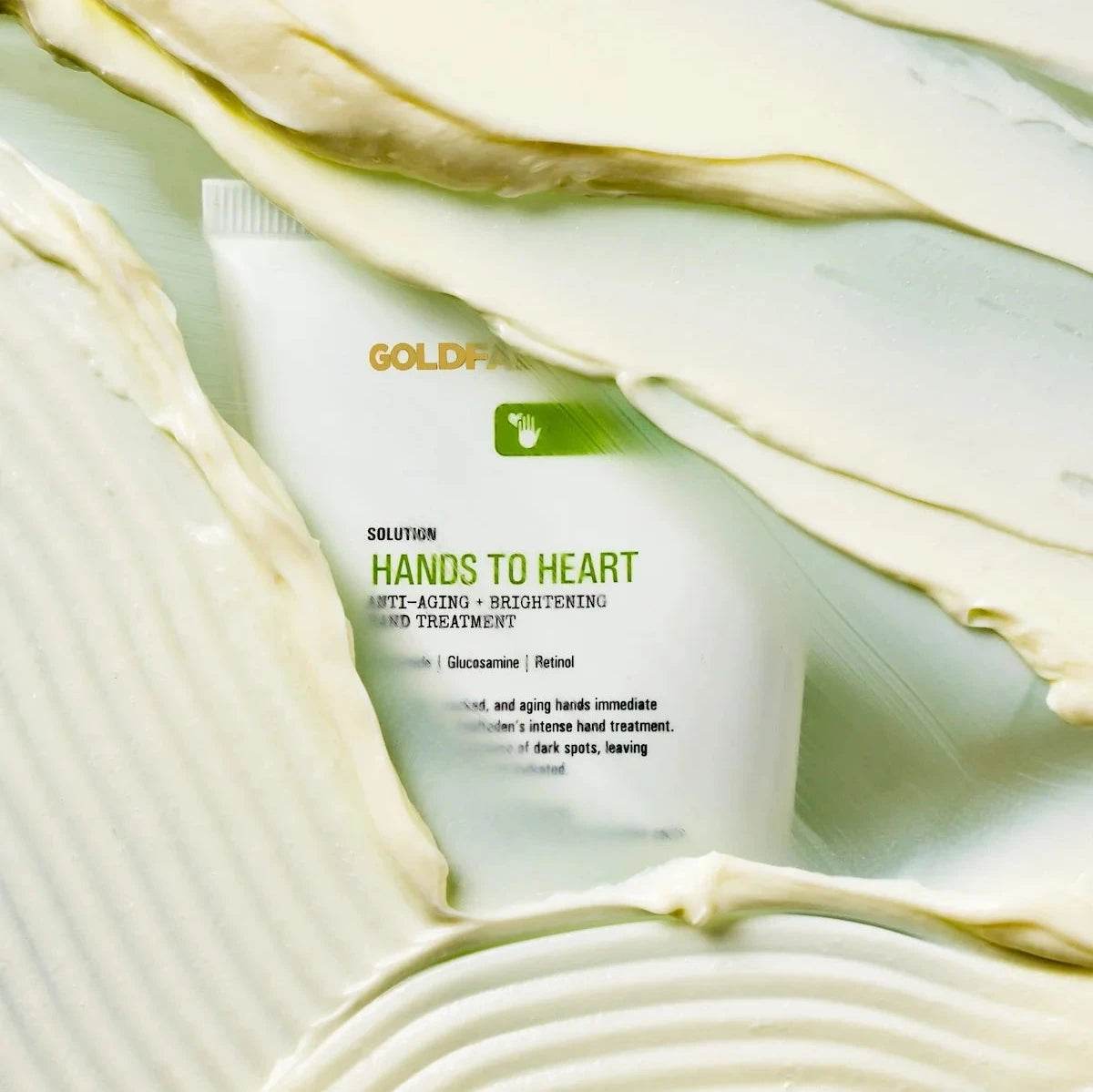 Goldfaden MD Hands to Heart Brightening Hand Treatment tube surrounded by creamy texture