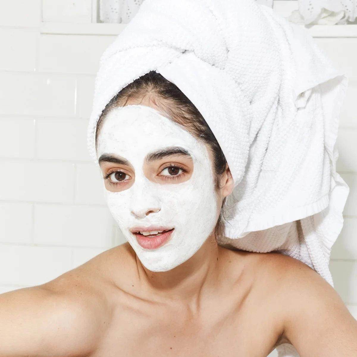 Woman wearing Goldfaden MD Facial Detox Mask Clarify & Clear Mask with towel wrapped on head