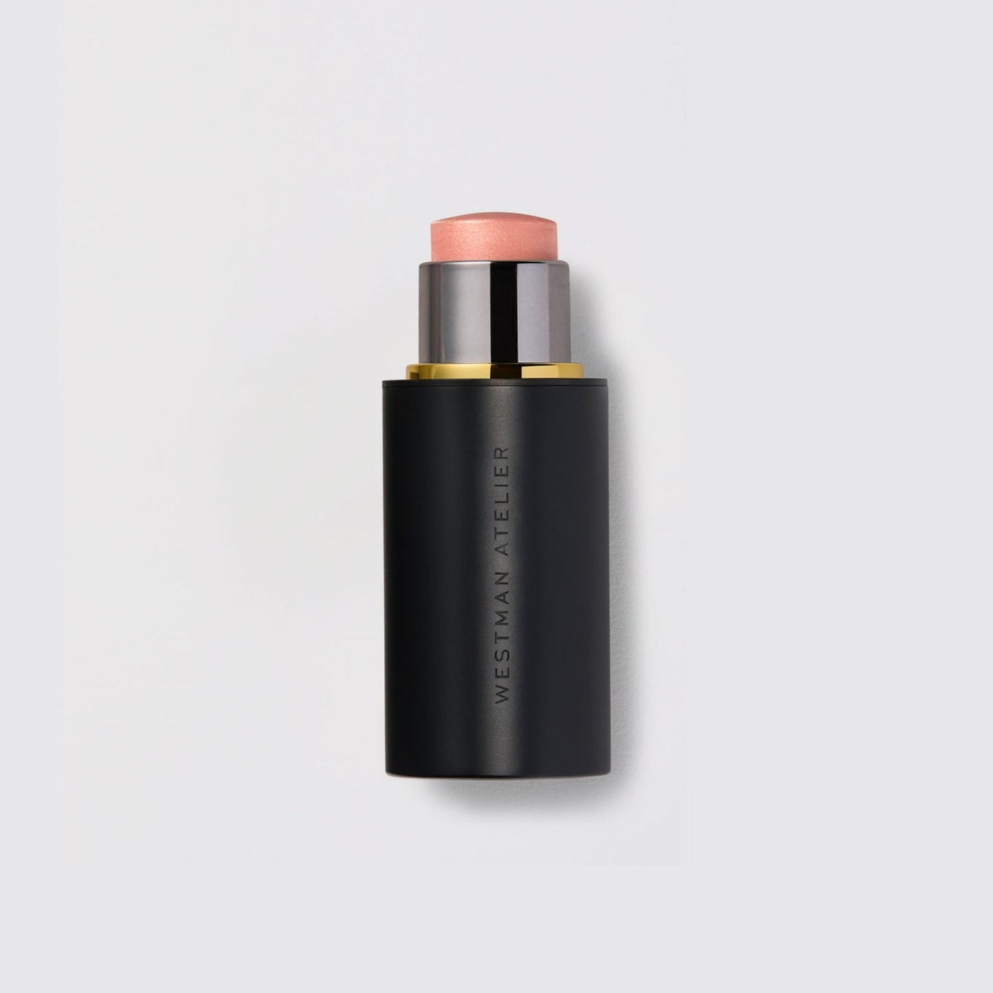 Westman Atelier Highlight Stick in a sleek black casing with a soft pink hue for a radiant finish