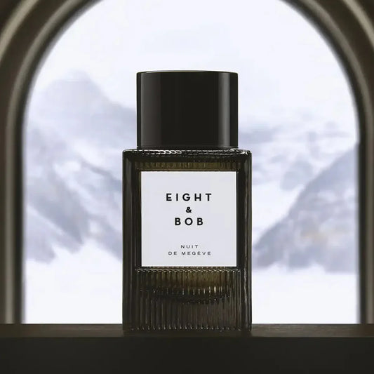 Perfume bottle labeled 'Eight & Bob' on a window sill with a blurred snowy landscape outside.