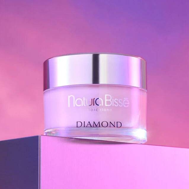 Natura Bisse Diamond Age Defying Body Cream in a pink jar with silver lid on pink background