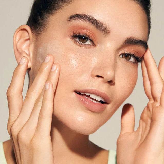 Model applying Natura Bisse Cleansing Exfoliating Gel on her face for radiant skin