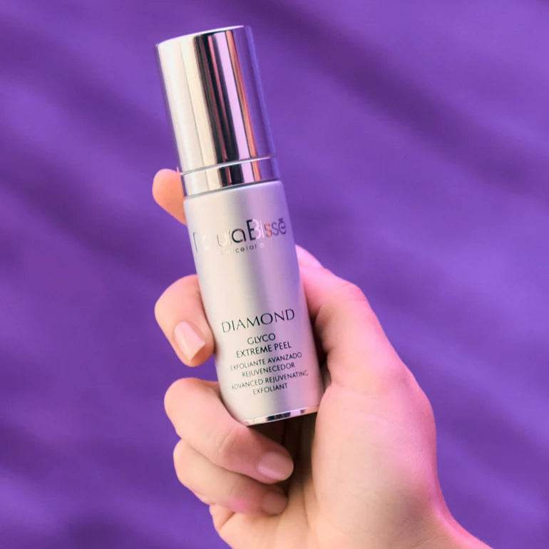 Natura Bisse Diamond Glyco Extreme Peel advanced rejuvenating exfoliant held in hand with purple background