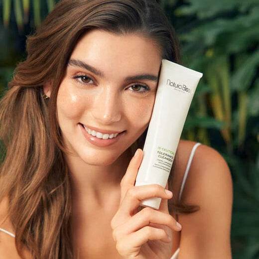 Natura Bissé NB-Ceutical Tolerance Cleanser in a woman's hand with a glowing smile