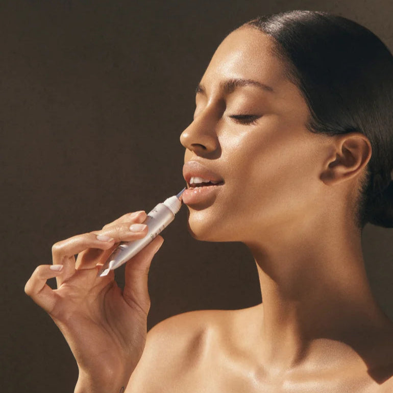Woman applying Natura Bisse Nourishing Lip Serum for smooth and hydrated lips
