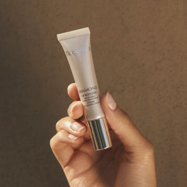 Natura Bisse Nourishing Lip Serum Diamond Lip Booster held in hand with metallic silver cap