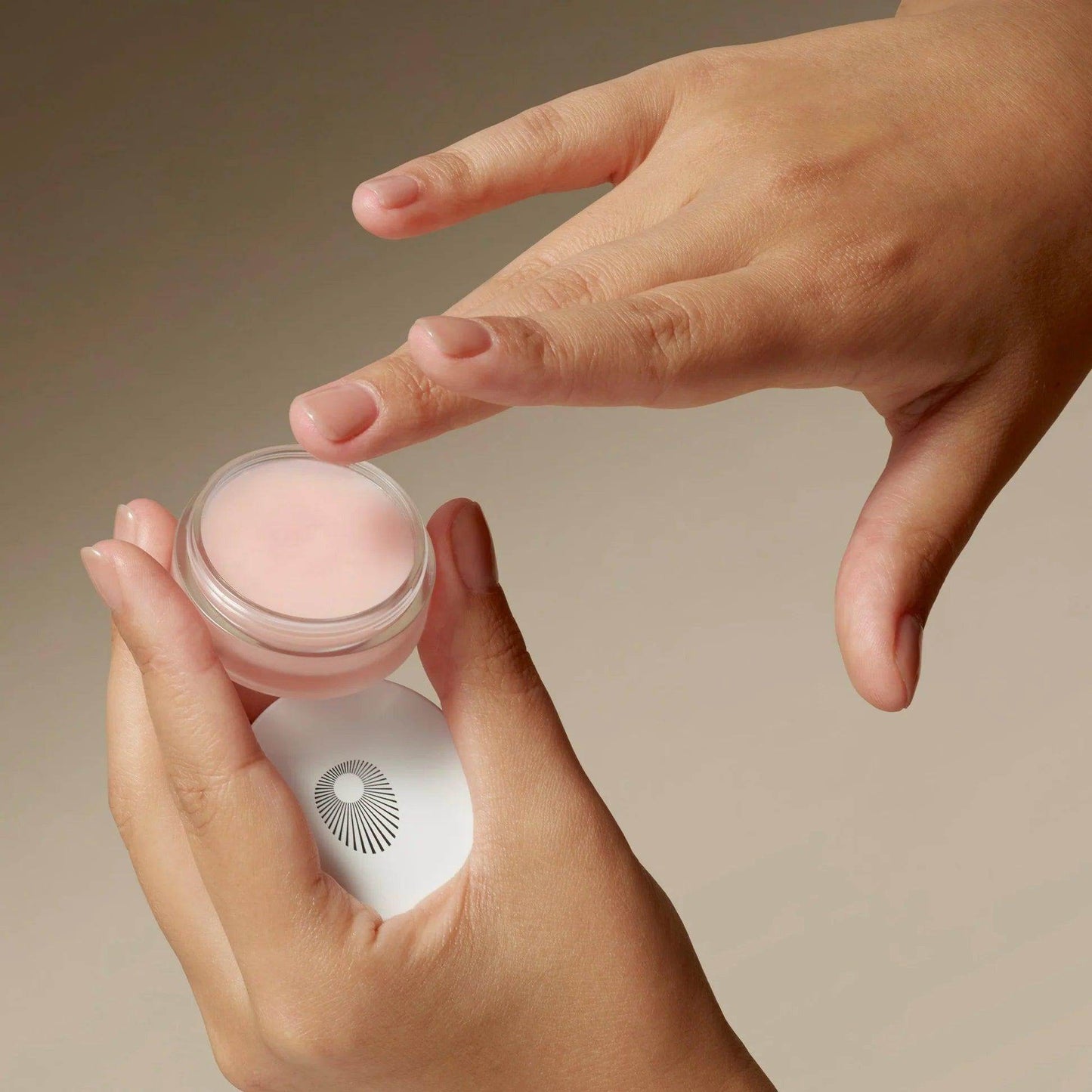 Omorovicza Perfecting Lip Balm in a clear jar, applied with gentle finger touch for hydration
