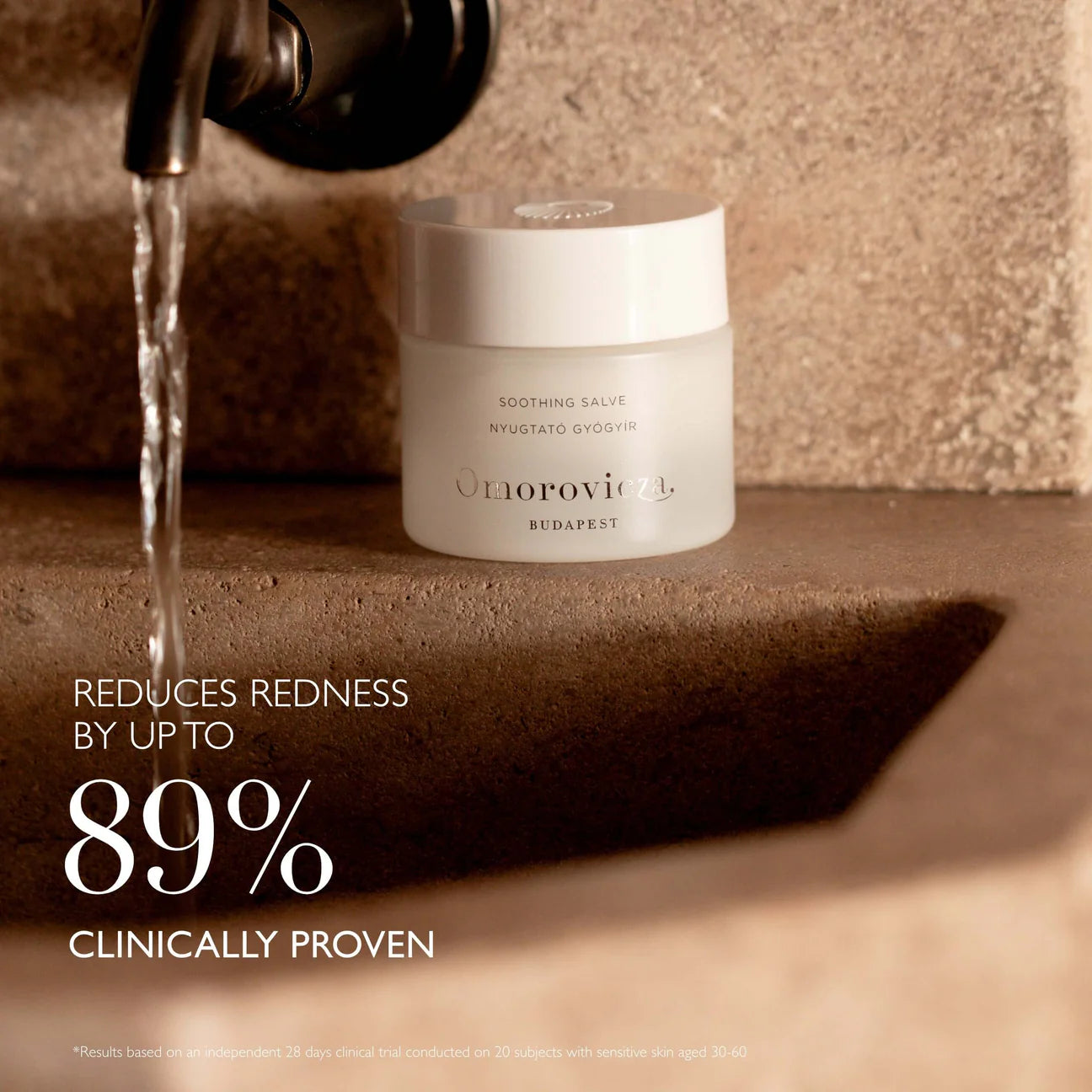 Omorovicza Soothing Salve jar on stone sink next to running faucet reduces redness clinically proven