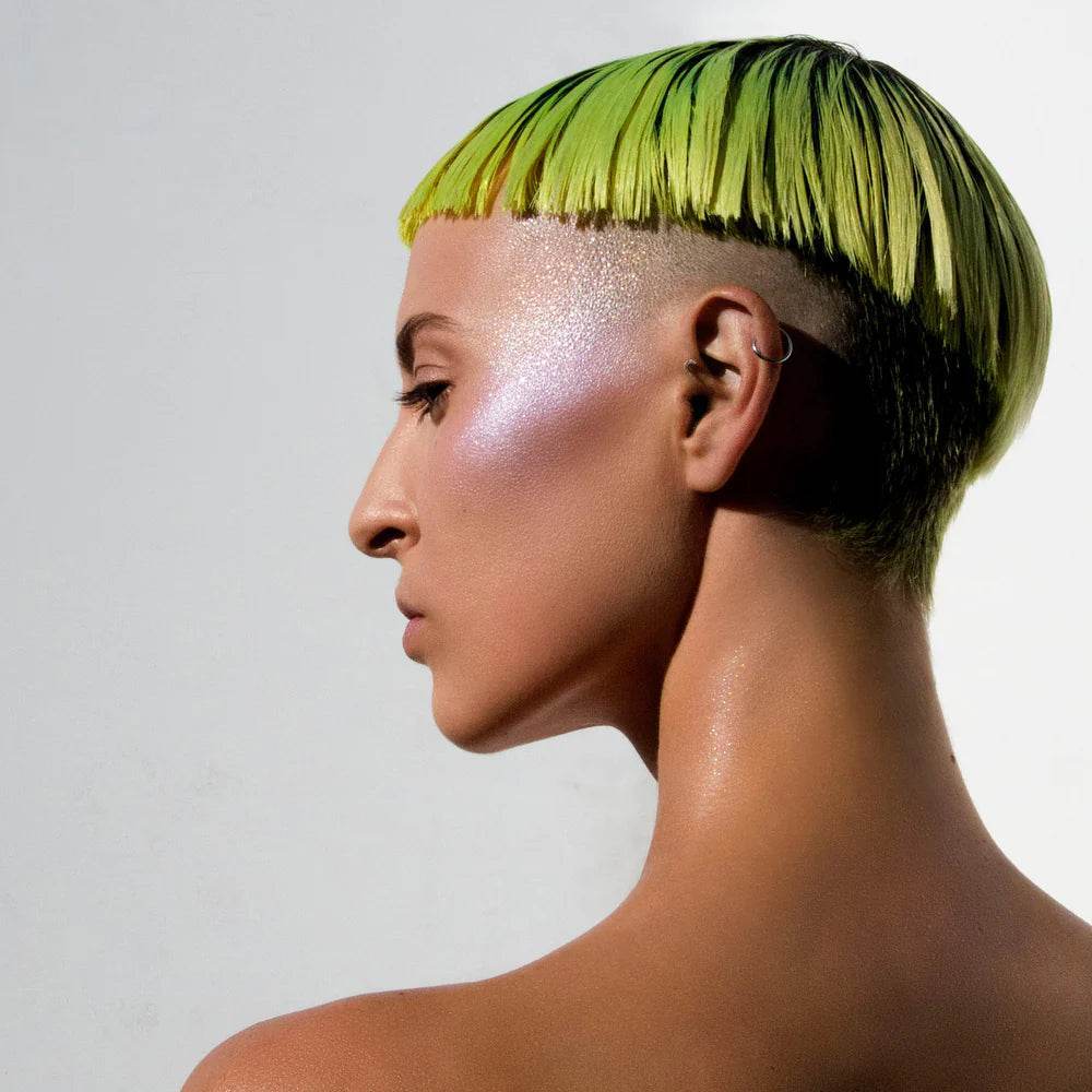 Model showcasing a shimmering glow using Highlight Intensifier on cheekbones with vibrant green hair