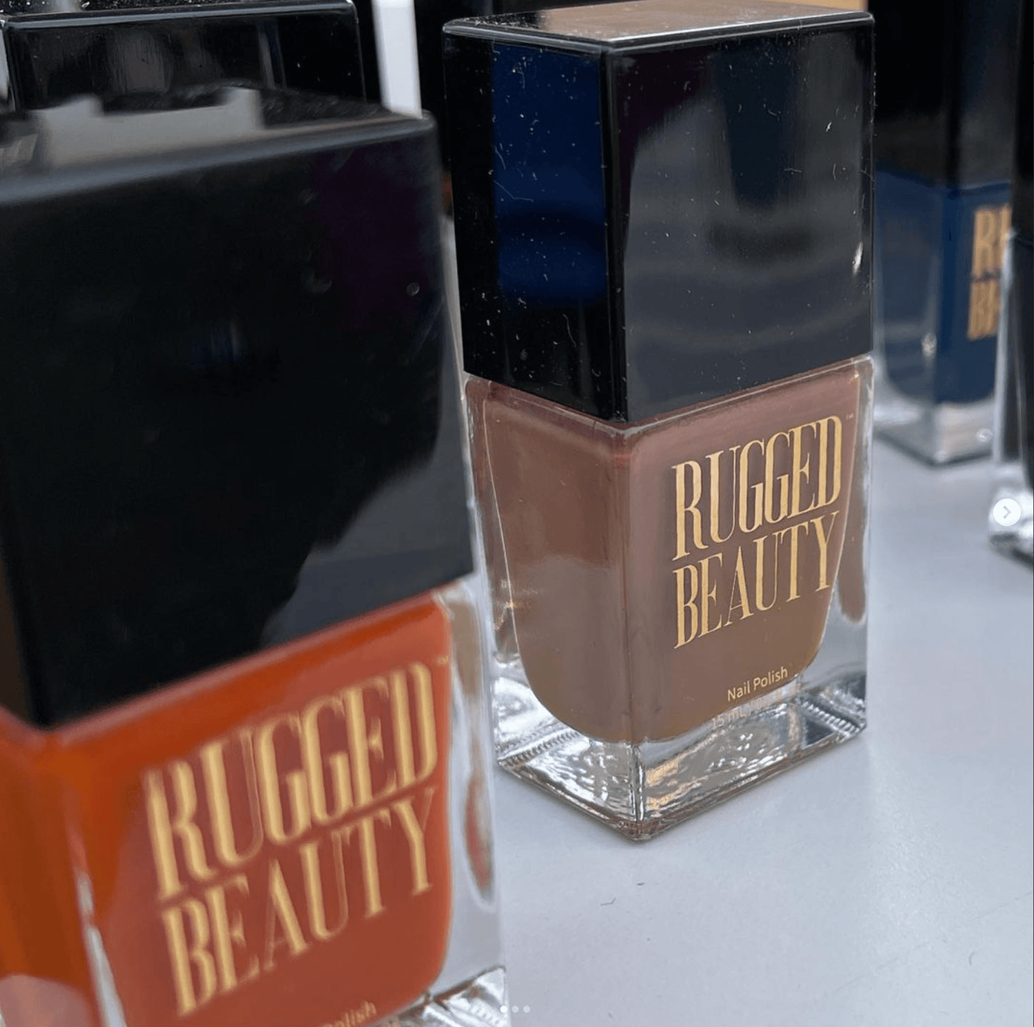 Close-up of Rugged Beauty nail polish bottles in various earthy shades with black caps on display