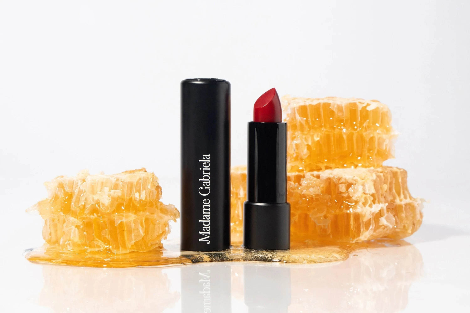 Madame Gabriela clean lipstick in black tube with bold red color surrounded by golden honeycomb and honey