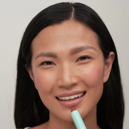 Woman holding a light blue makeup product with brand names displayed below.