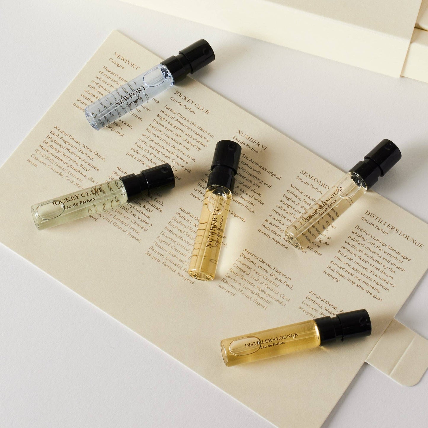 Five small perfume bottles on a piece of paper with text