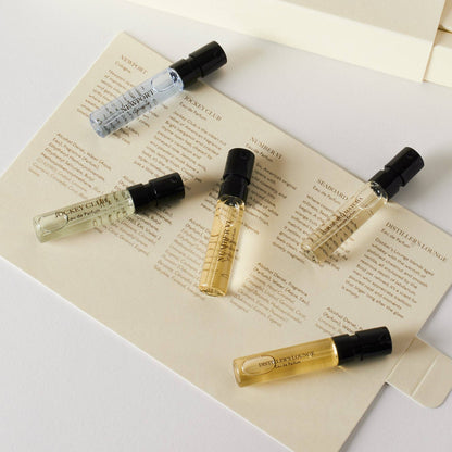 Five small perfume bottles on a piece of paper with text