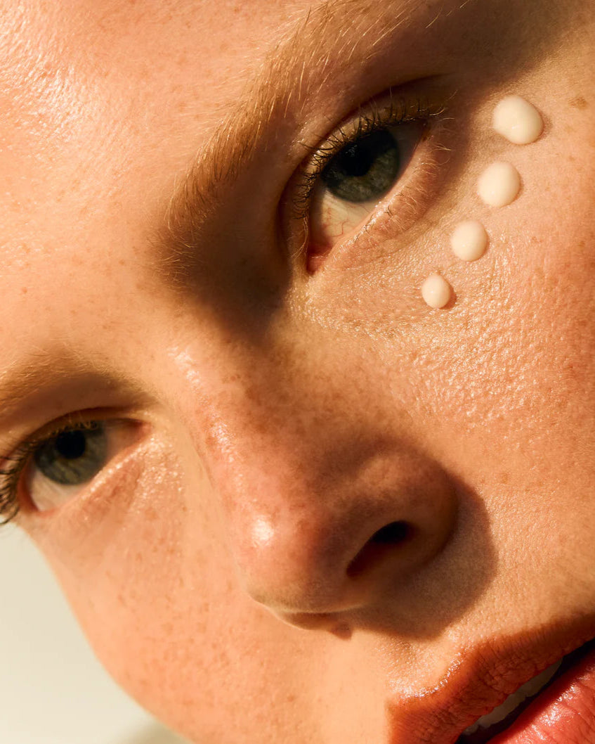 Close-up of a person's face with light makeup on a neutral background