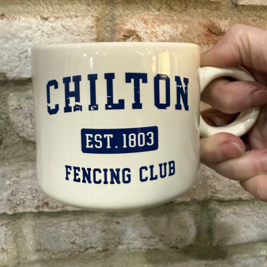 Mug with 'Chilton Fencing Club' text held against a brick wall