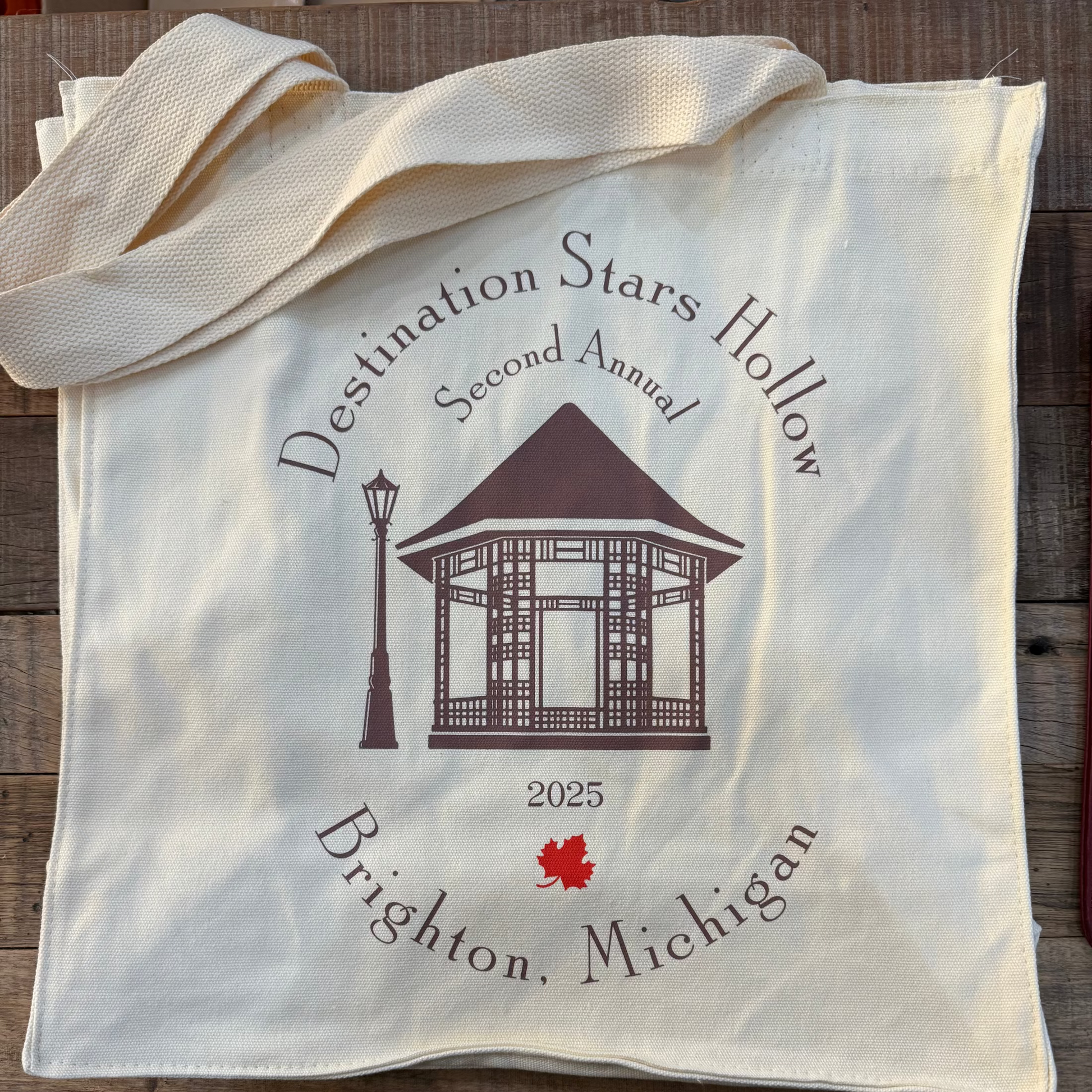 White tote bag with 'Destination Stars Hollow' design on a wooden surface