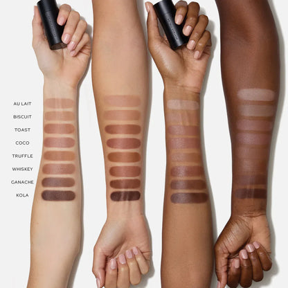 Four arms with different skin tones displaying makeup swatches on a white background.