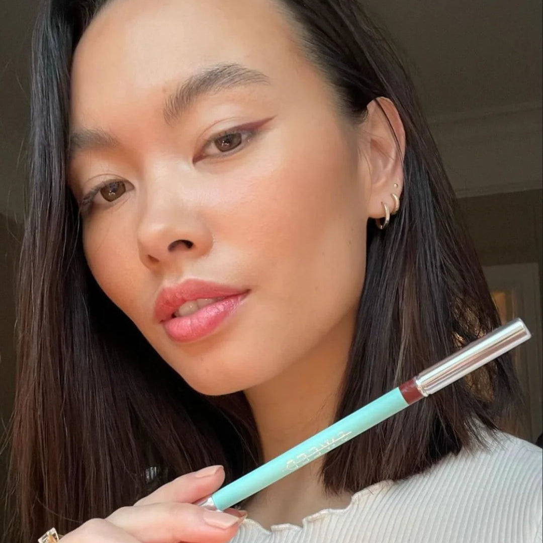 Woman holding a makeup pencil with a blurred background