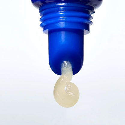 Blue bottle cap with a small amount of beige liquid on a white background