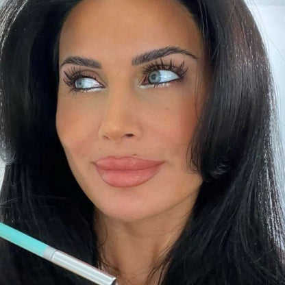 Woman with makeup brush near face against a neutral background