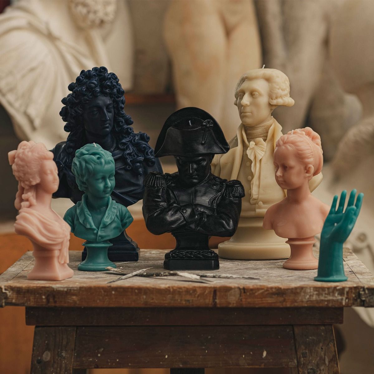 Trudon Cherub Hand candle alongside a collection of artistic busts in various colors