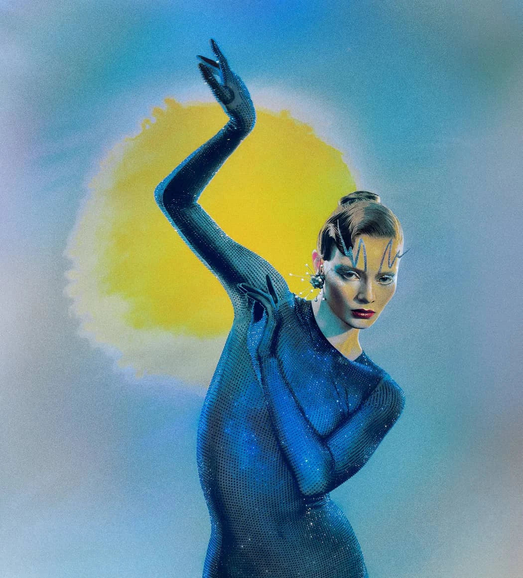 Model dressed in blue performing arts attire, representing the Unique Gourmand Fragrance by Cirque Du Soleil