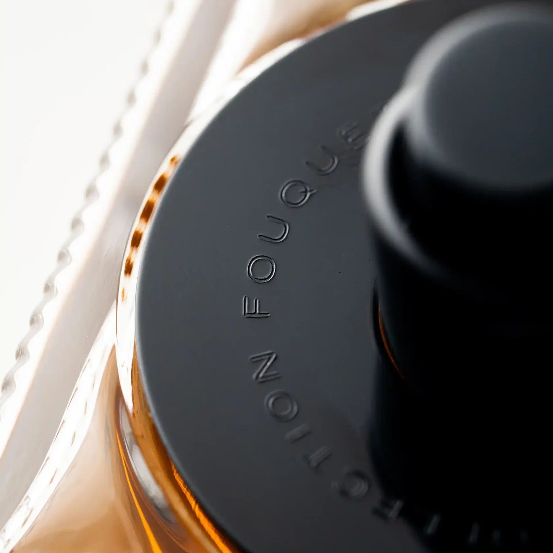 Close-up of a black and gold product with 'Fouquet' branding on a white background