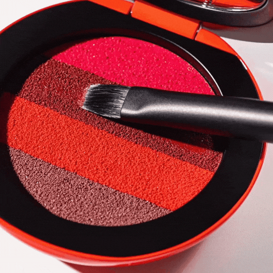 Westman Atelier Elegant Lip Brush resting on a vibrant striped lip color palette in shades of red and brown
