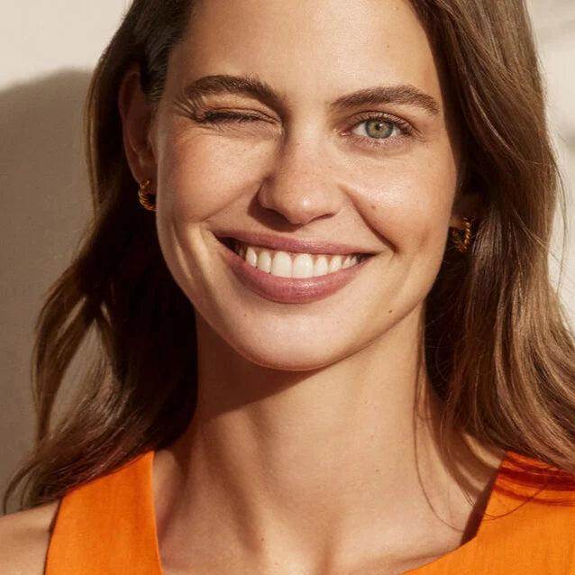 Smiling woman with clear skin highlighting Natura Bisse Gel With Ginseng And Vitamin C skincare product benefits