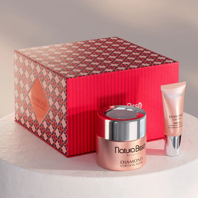 Cosmetic set with a red box, jar, and tube on a white pedestal against a neutral background
