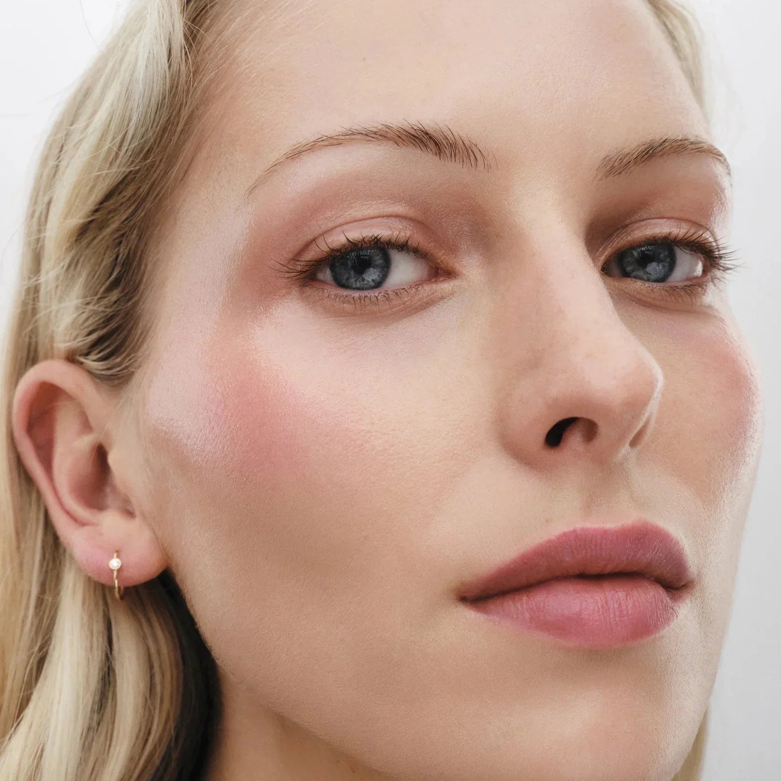 Close-up of a model showcasing a radiant glow with Westman Atelier Highlight Stick for a natural finish