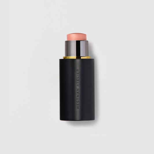 Westman Atelier Highlight Stick in a sleek black casing with a soft pink hue for a radiant finish