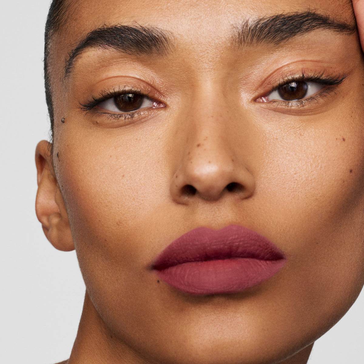 Model wearing Westman Atelier Luxury Matte Lipstick in a deep mauve shade for a bold look