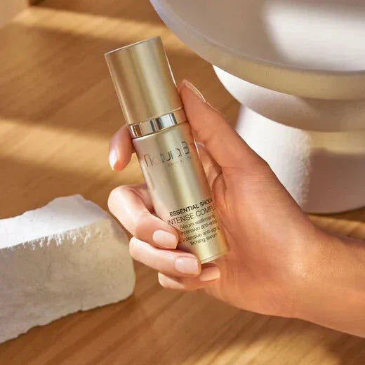 Natura Bissé Essential Shock Intense Complex in a hand, showcasing the Anti-Aging Firming Serum for youthful skin