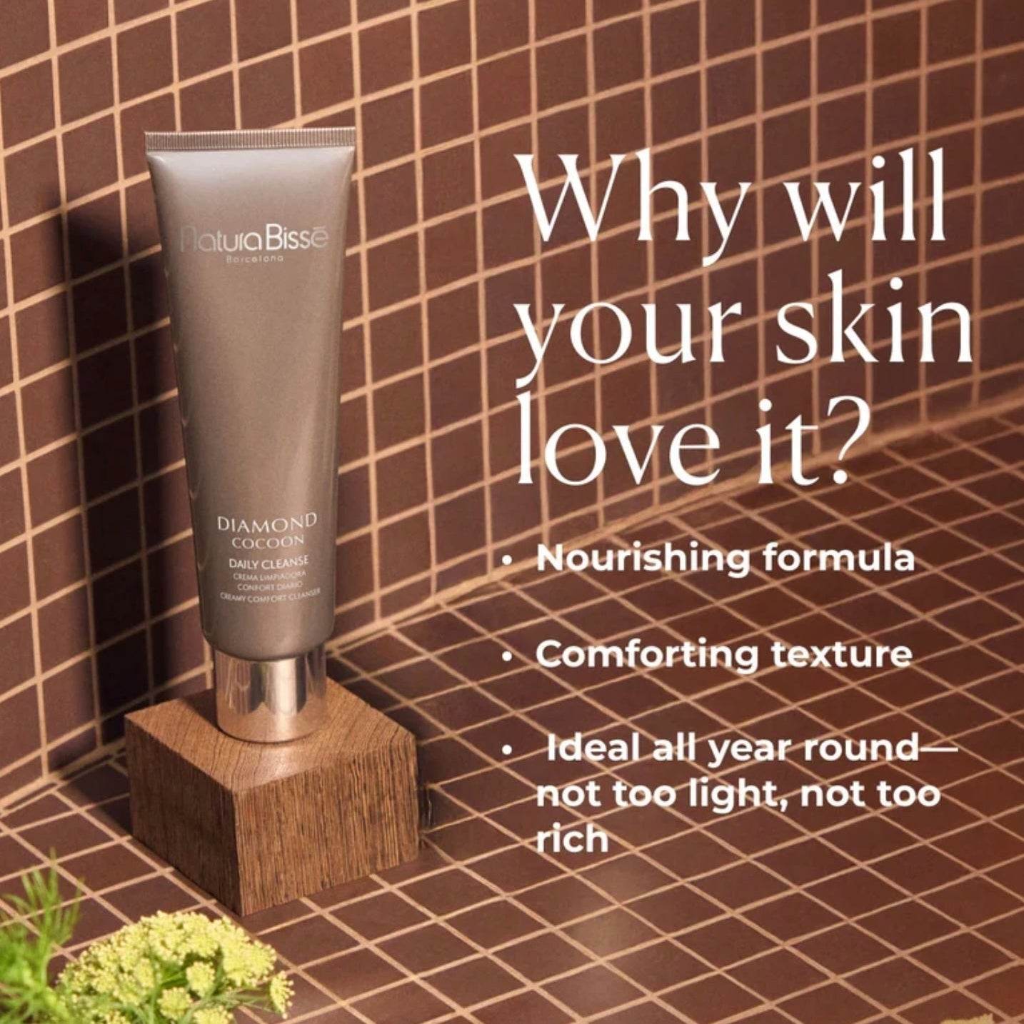 Natura Bissé Comfort Creamy Cleanser in a sleek tube on a wooden stand with a textured background