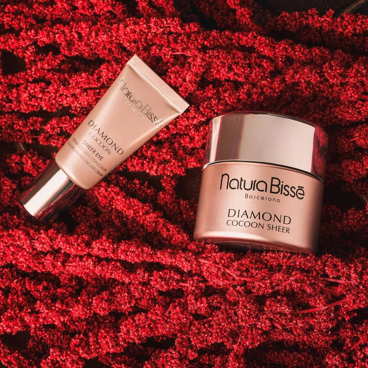 Diamond Cocoon Sheer Holiday Set featuring Natura Bissé cream and serum on a textured red background