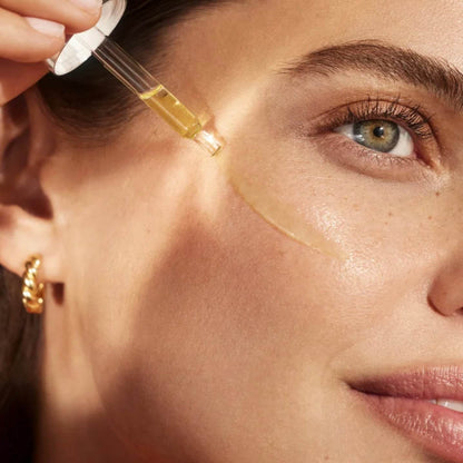 Model applying Natura Bisse Firming Serum with Vitamin C to enhance skin radiance and firmness