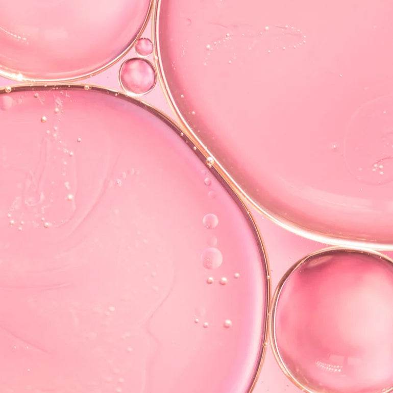 Natura Bissé Hydrating Revitalizing Essence with a smooth pink liquid texture in droplets